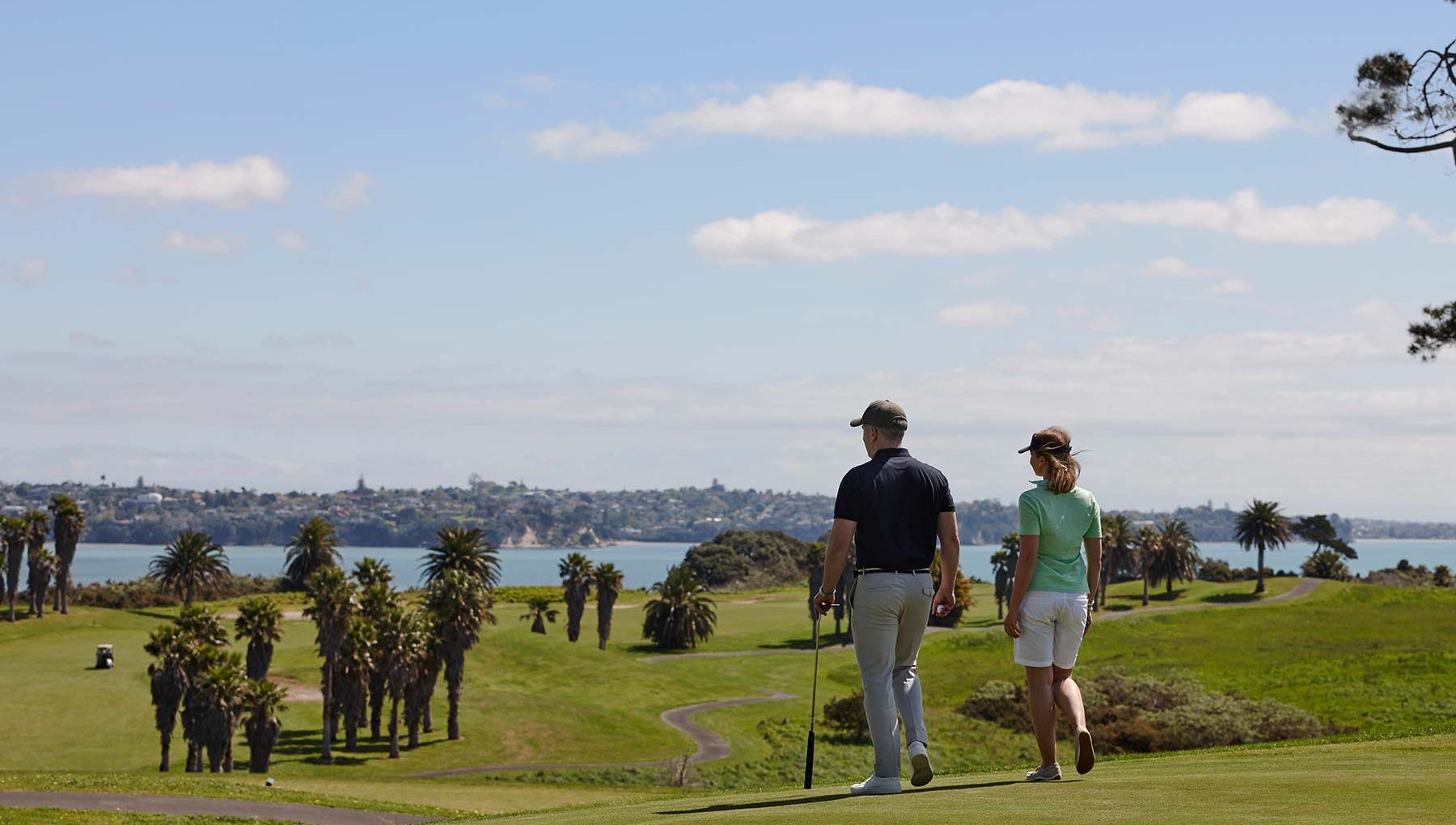 Happy couple strolling on a scenic golf resort near Auckland - Ideal Event Venues Auckland.