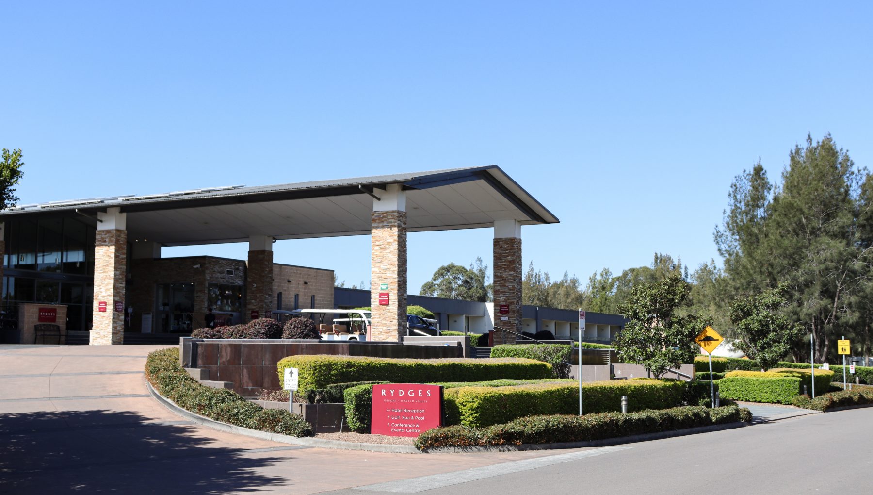 Photograph of the main entry with clearly visible signage, featuring a driveway leading up to the main entrance.